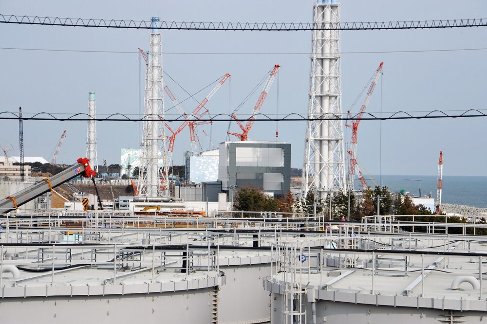 Nuclear plant with striped stacks and many cylindrical tanks in the foreground